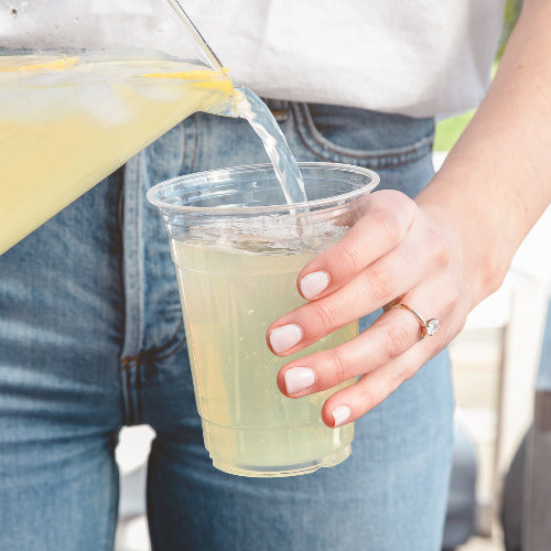 Woman pouring lemonade into a 16oz Compostable Party Cup.